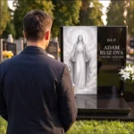 hombre frente a panteón moderno de granito negro con panel de cristal de Jesús y lirios blancos