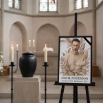 Custom photo for memorial displayed on easel with floral design at funeral service