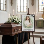 Custom memorial portrait panel with name and dates displayed on easel beside casket at funeral