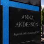 Blue asymmetric glass cross bonded to a black granite headstone