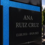 Cruz asimétrica de vidrio azul pegada a una lápida de granito negro