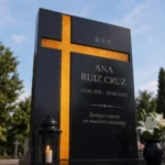 Cruz asimétrica de vidrio dorado pegada a una lápida de granito negro