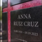 Cruz asimétrica de vidrio rojo pegada a una lápida de granito negro