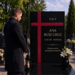 Cruz asimétrica de vidrio rojo pegada a una lápida de granito negro