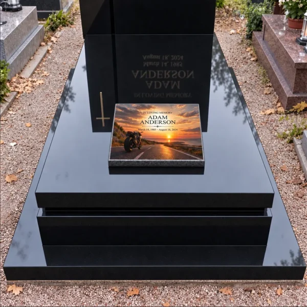 Memorial plaque with a motorcycle on the road at sunset on the slab of a black grave, front view