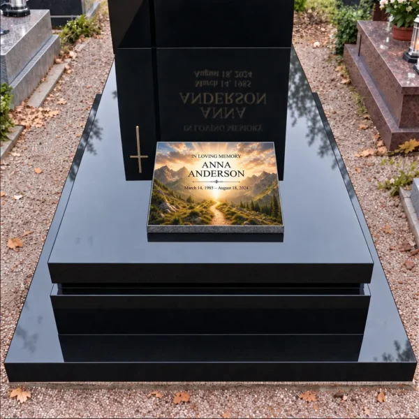 Memorial plaque with a mountain trail motif on the slab of a black grave, front view