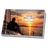 Placa conmemorativa de vidrio con un navegante en la cubierta de un velero al atardecer, sobre base de granito