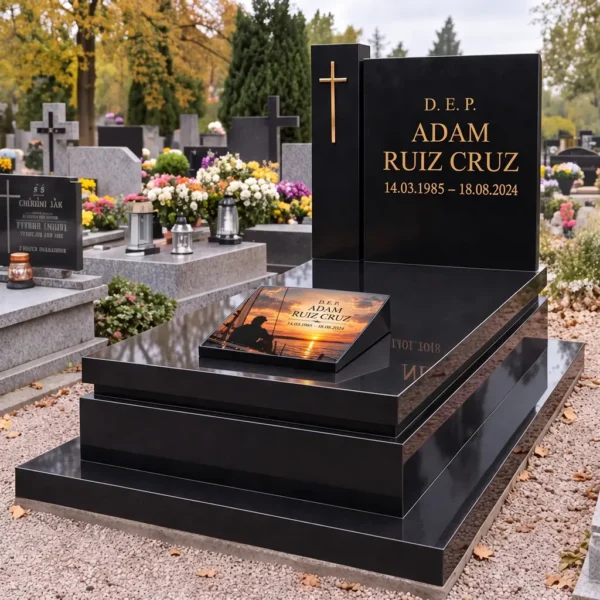 Placa conmemorativa con un navegante en un velero en la losa de una lápida negra con cruz y letras doradas