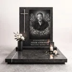 Black and white memorial plaque with photo of deceased set into a granite headstone