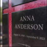 Red asymmetric glass cross bonded to a black granite headstone